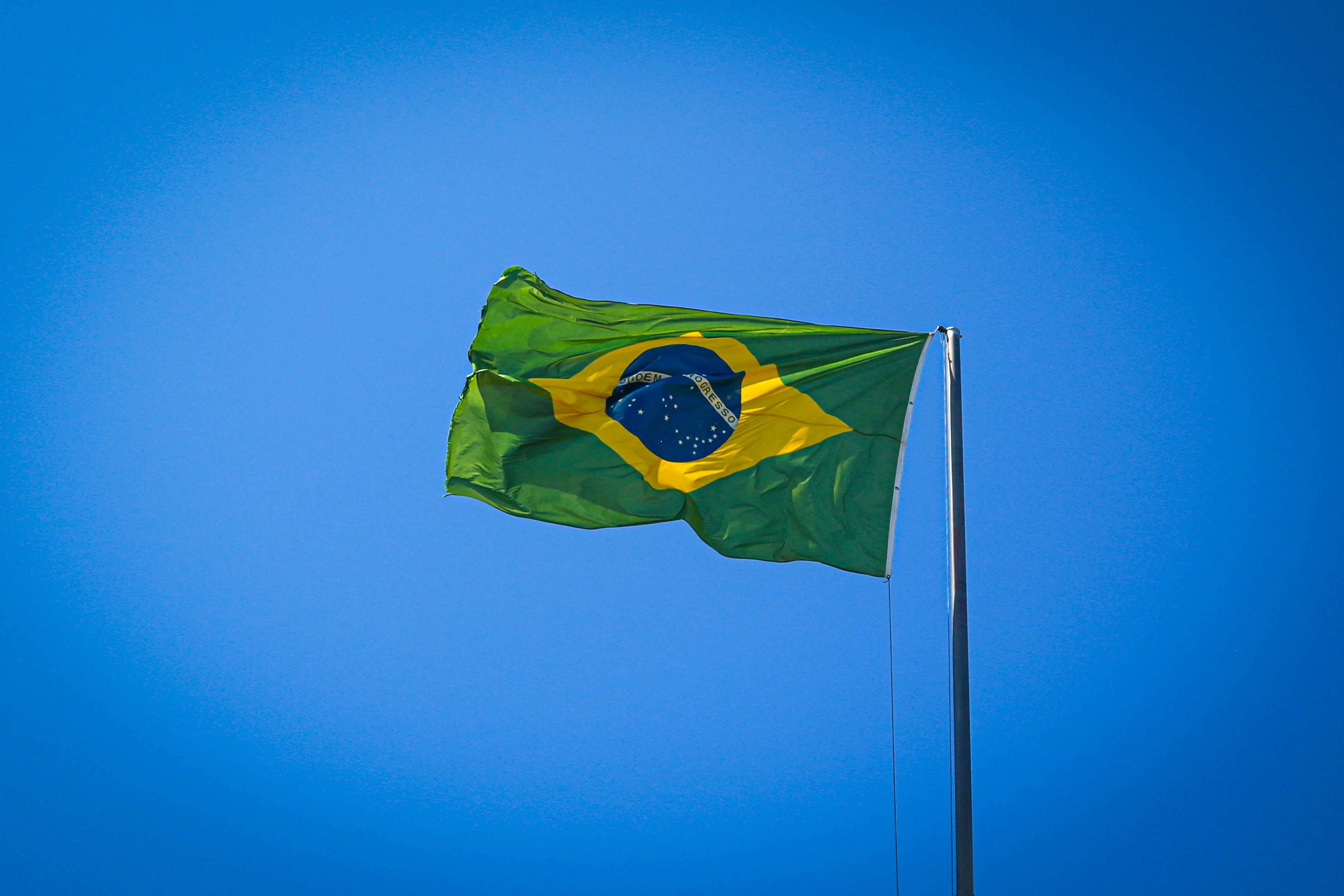 The flag of Brazil against a clear, hazy sky.