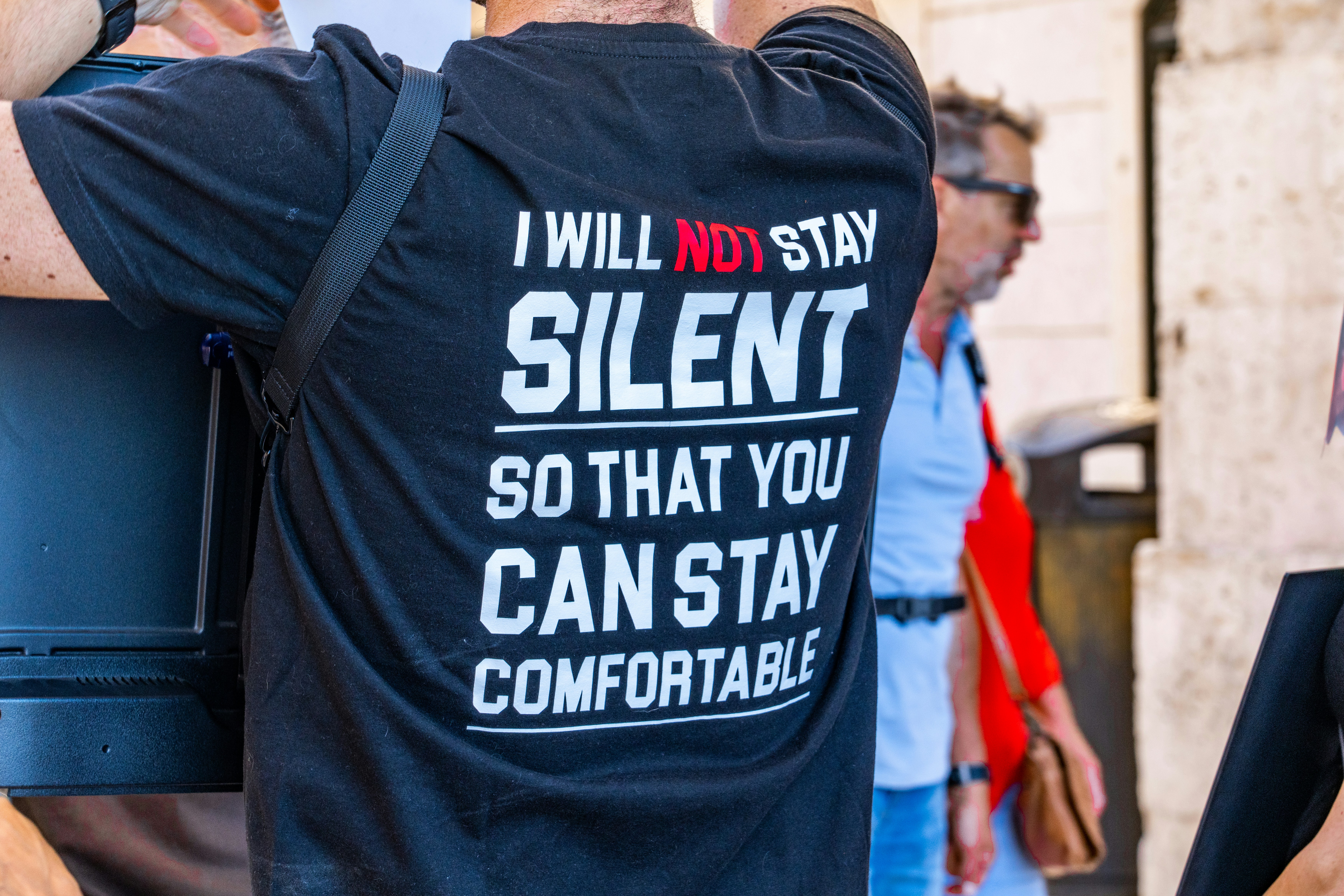 The back of a person's shirt with text that says, "I will not stay silent so that you can stay comfortable."